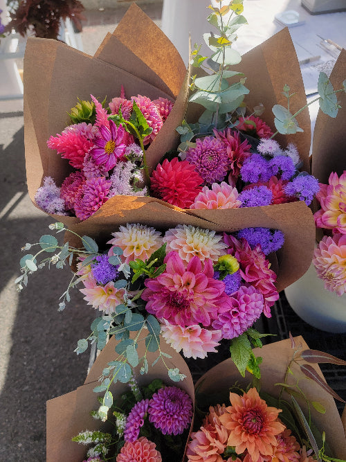 Colorful bouquet of flowers in brown paper packaging on a blurred background