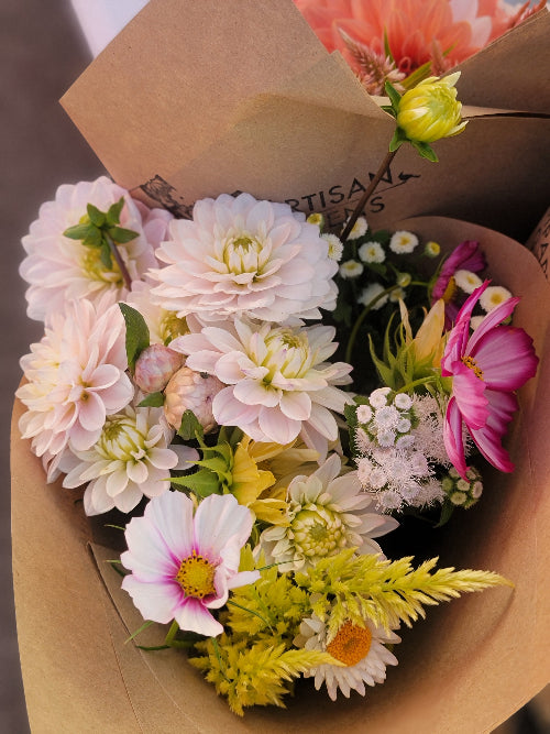 Bouquet of flowers wrapped in brown paper with visible brand name.